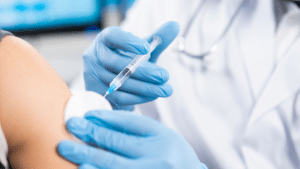 Gloved hand administering an injection into a patient's arm