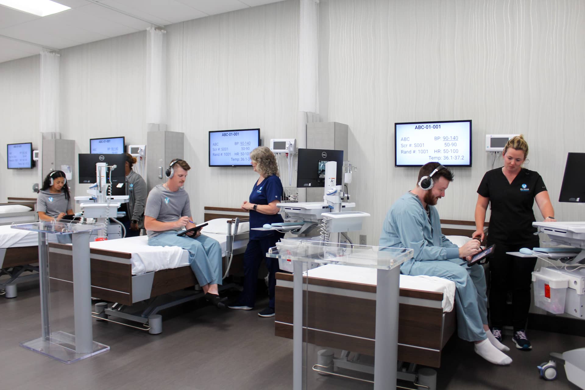 Clinical research exam room with medical monitors displaying patient vitals