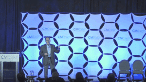 Blue hexagon-patterned stage backdrop with CM0360 degree logo