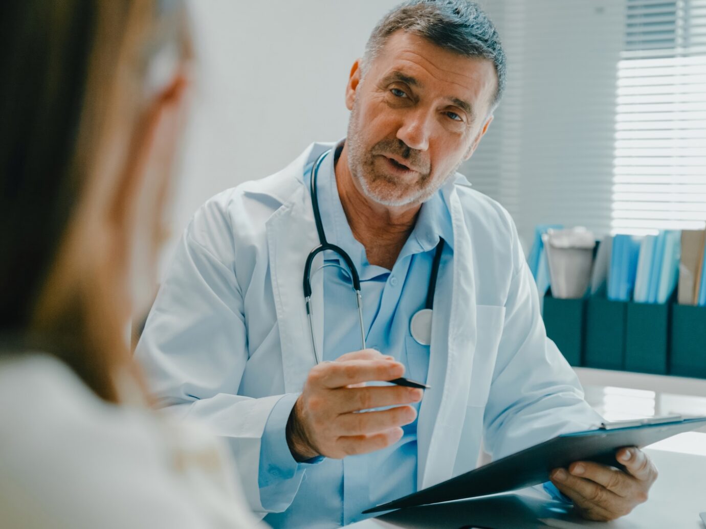 doctor in lab coat using digital tablet discusses medical test results with a patient