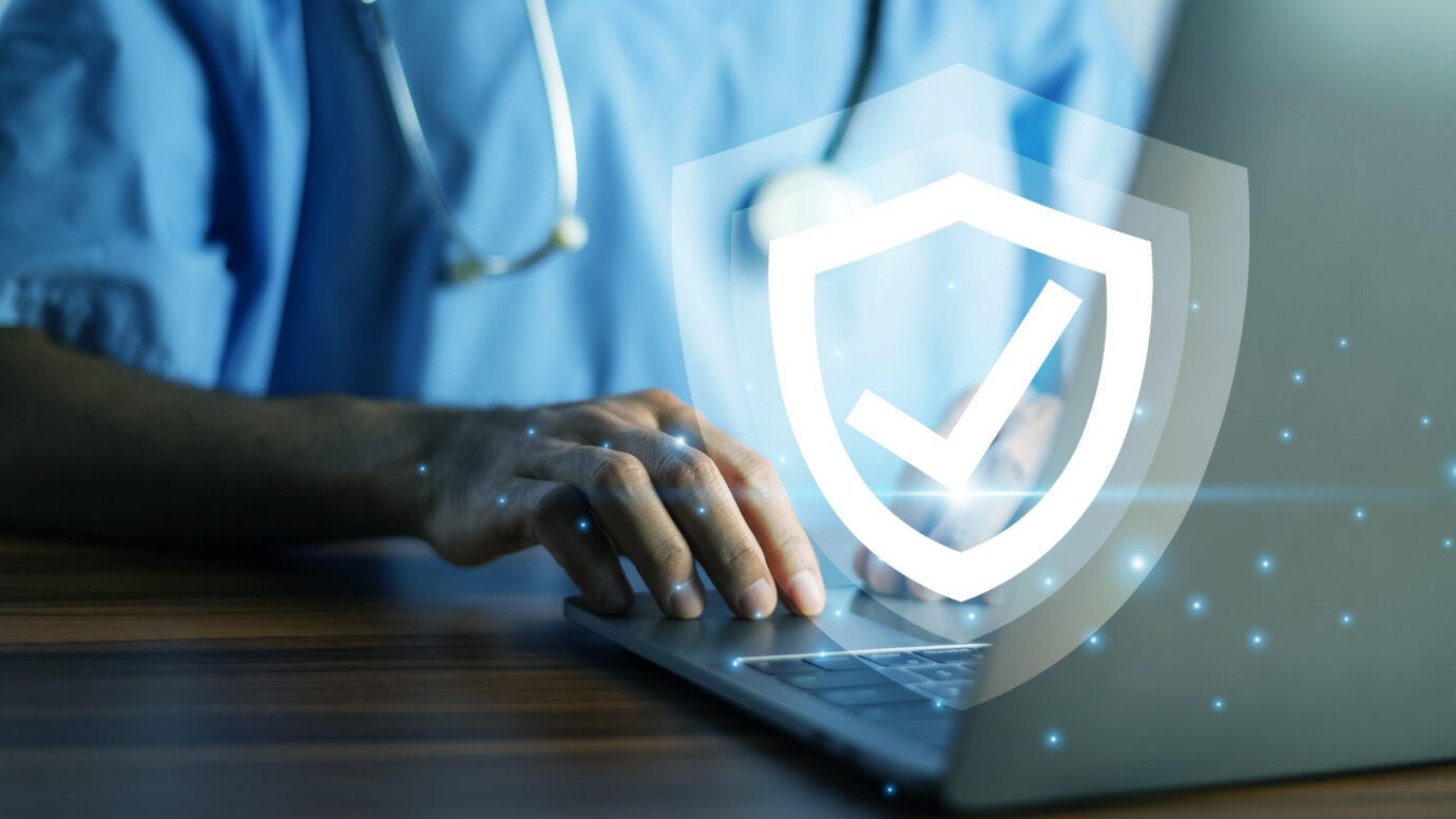 Doctor typing on a laptop with a glowing shield icon